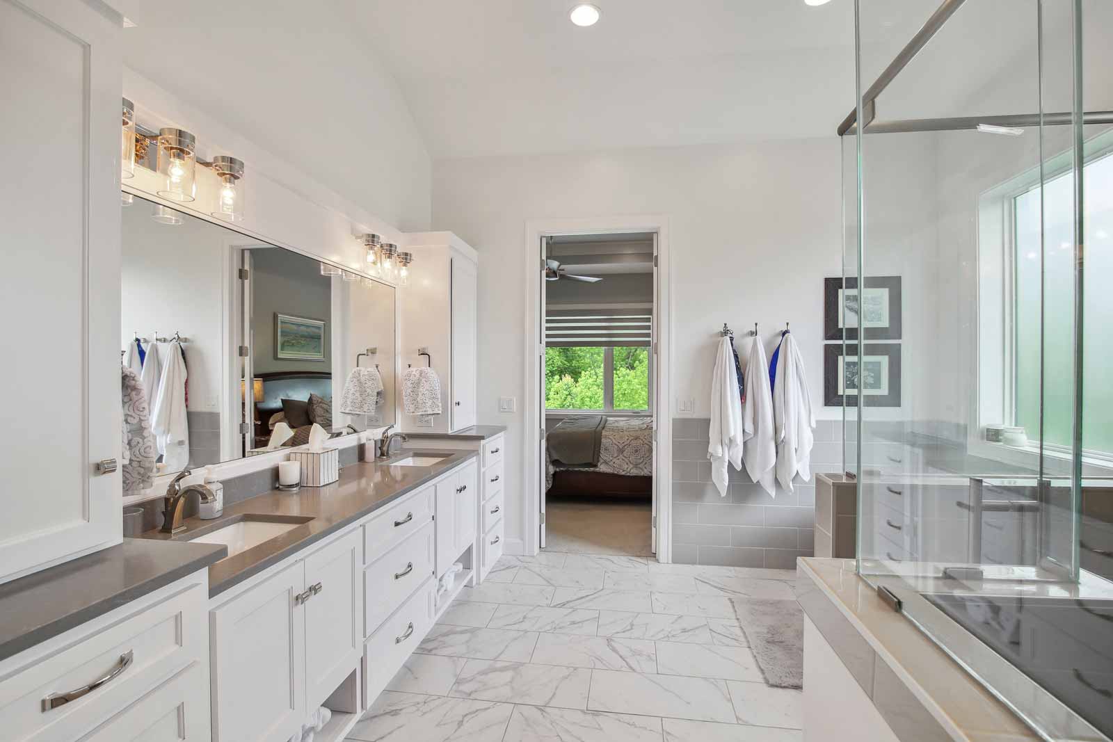Master bathroom with glass shower and large double vanity in Kenneth Estates home
